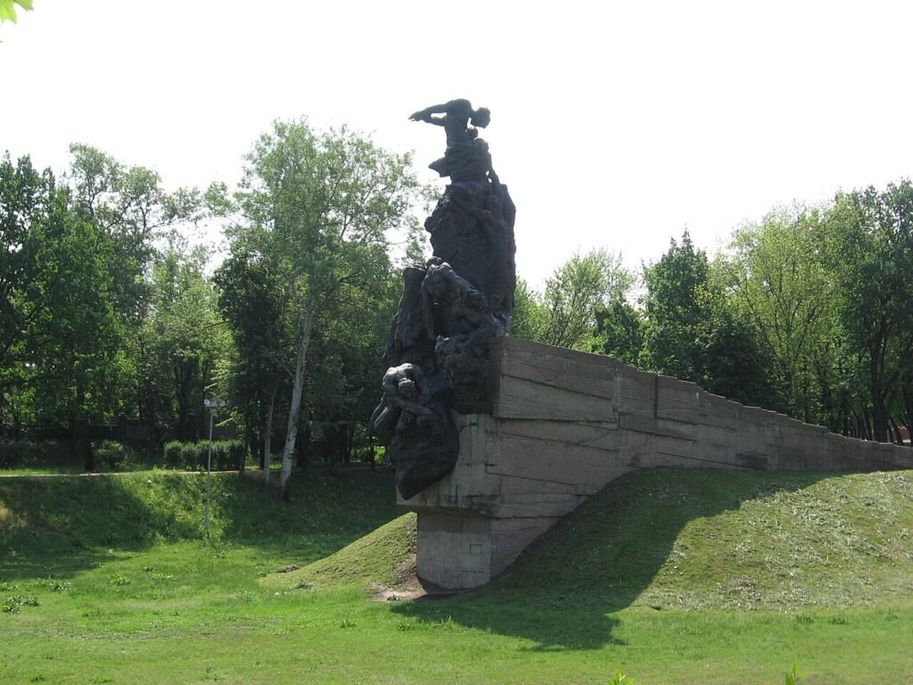 A monument of overlapping black bronze figures standing atop a concrete wall
