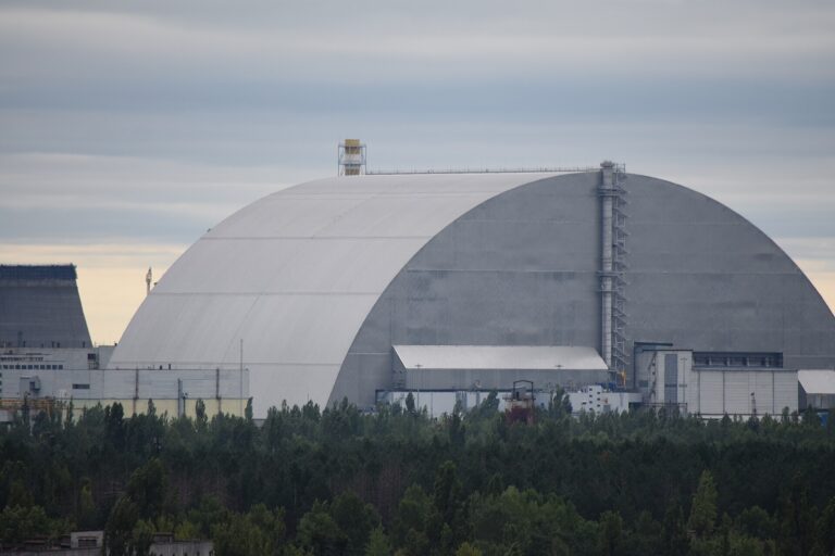 森の向こうに、巨大なアーチ形の新安全閉じ込め構造物(NSC)がチョルノービリ原発4号炉を覆っている
