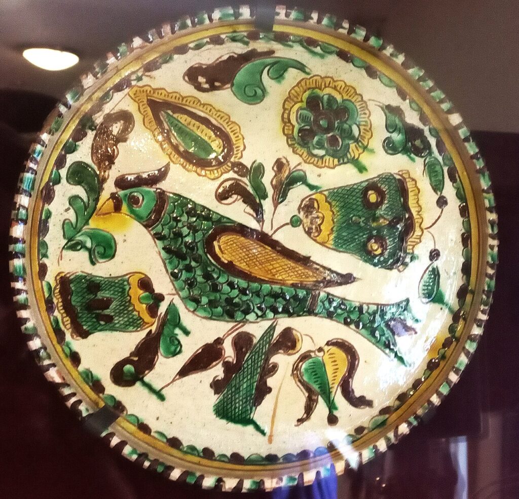 A round ceramic plate painted with a bird motif in green and brown