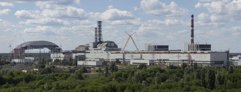 チョルノービリ原子力発電所の敷地を横に見渡したパノラマ。左に建設途中の新しい閉じ込め構造物、中央付近に4号機