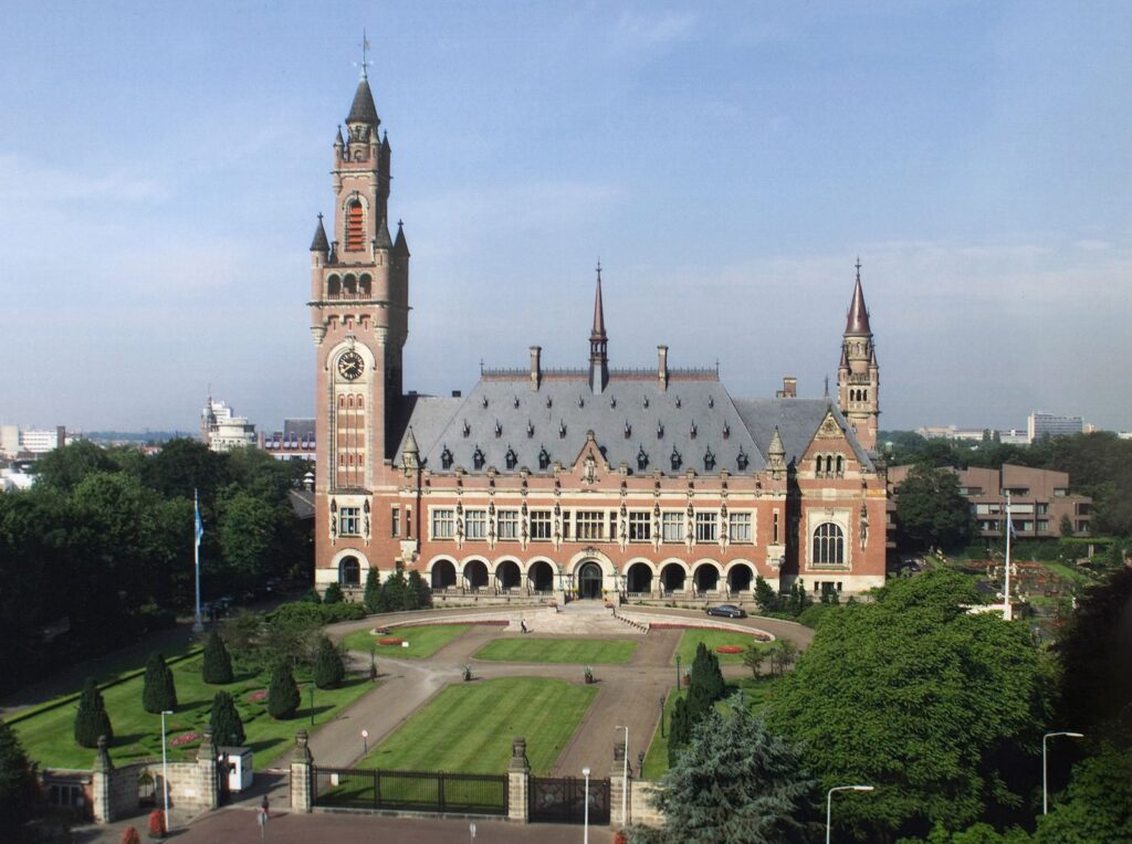 A red-brick palace building with a tower, with a broad lawn in front