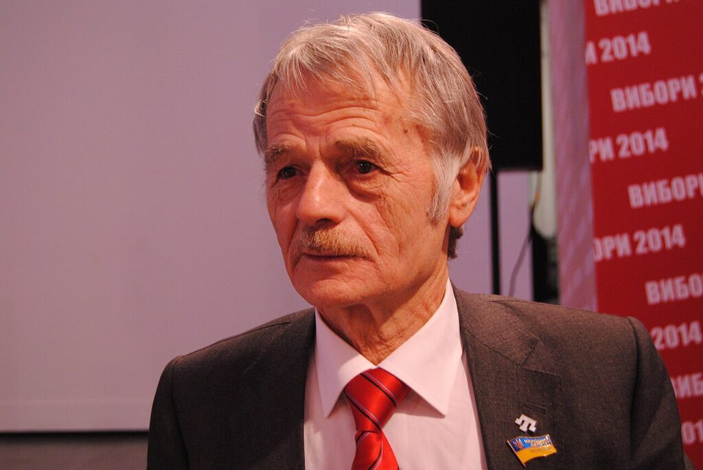 A portrait photograph of an elderly man with gray hair and a mustache