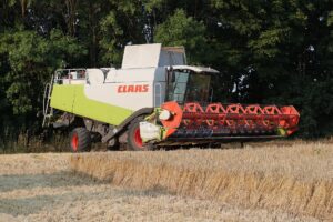 A combine harvester parked in a wheat field where much of the crop has already been cut