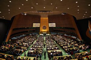 国連本部の総会議場。正面の演壇と国連の紋章、並んだ議席