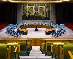 馬蹄形の演壇と、ノルウェーの壁画を背にした国連安全保障理事会の議場。円卓には15の理事国の席が並ぶ