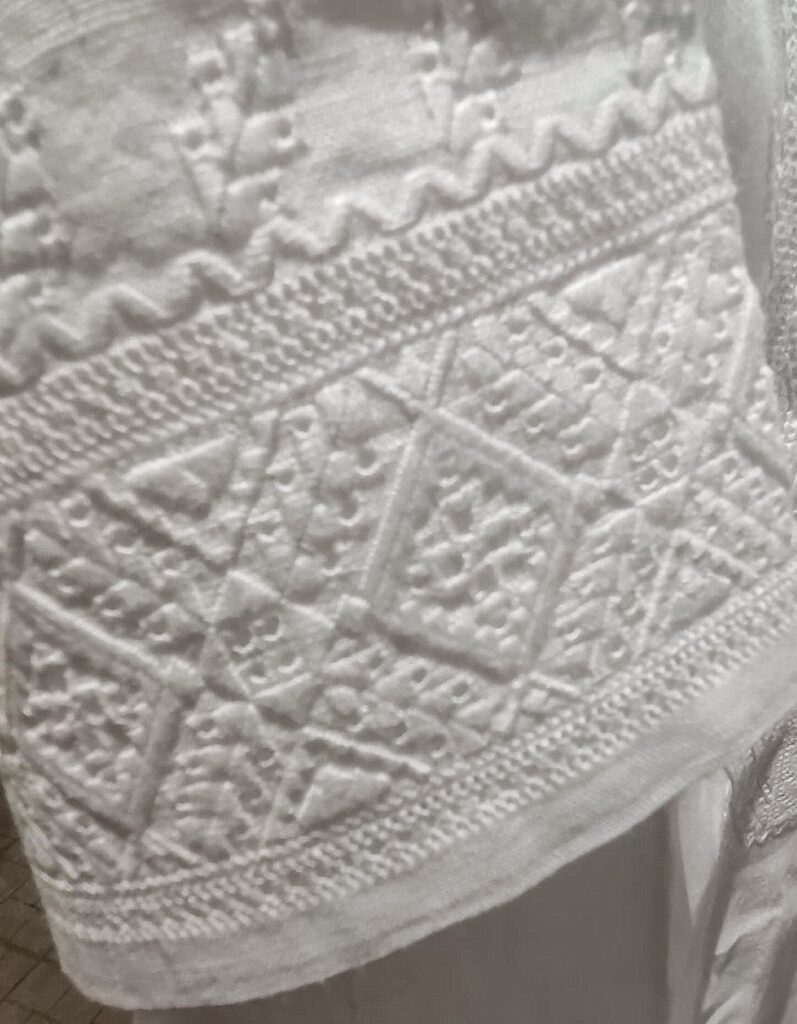 Embroidery stitched in white thread on white cloth
