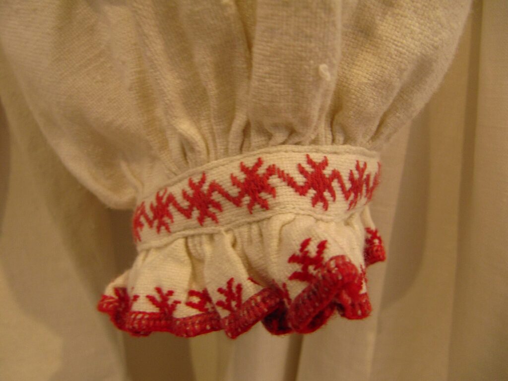 The cuff of a white shirt embroidered with red thread